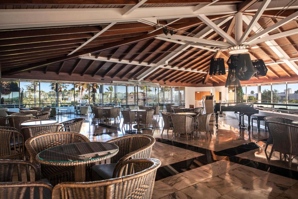 Mūsdienīgs restorāns ar plašu atvērto telpu un koka griestiem, kurā ir vīnogulāju stila mēbeles un lieli logi, kas paver skatu uz apkārtējo ainavu.