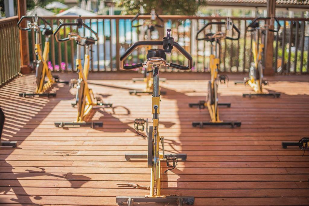 Dzeltenu velosipēdu rinda uz terases, kas ir ideāla vieta sportiskām aktivitātēm un grupu treniņiem. Rūpīgi sakārtotas velosipēdu stacijas, kas aicina uz aktīvu dzīvesveidu.