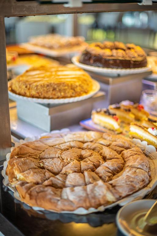 Saldumu bufete ar dažādiem desertiem, tostarp spirālveida pīrāgs priekšplānā un citas kūkas fonā.