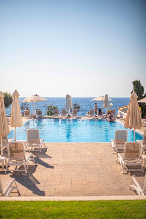 Peldbaseins ar saulessargiem un atpūtniekiem, redzams jūras skats un saulaina debess. Ideāla vieta relaksācijai un brīvdienām.