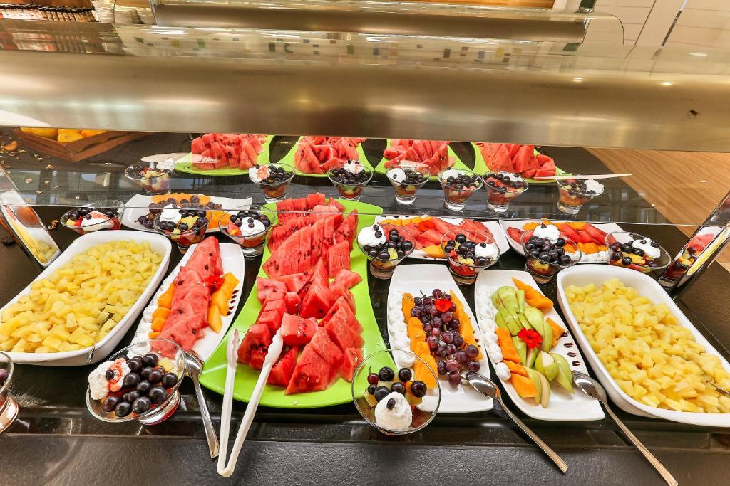 Krāsains augļu bufete ar melones, ananāsiem, vīnogām un krējuma desertiem. Ideāla izvēle vasaras svinībām un veselīgām uzkodām.