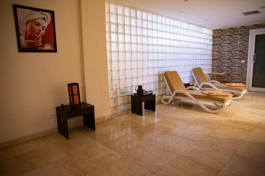 Relaksējoša spa telpa ar atpūtas krēsliem, lampu un mākslas darbu uz sienas. Gaisīga vide ar stikla blokiem un elegantu akmens apdari.