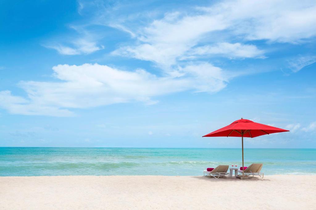 Sarkans saulessargs un atpūtas krēsli piekrastē, Angsana Laguna Phuket