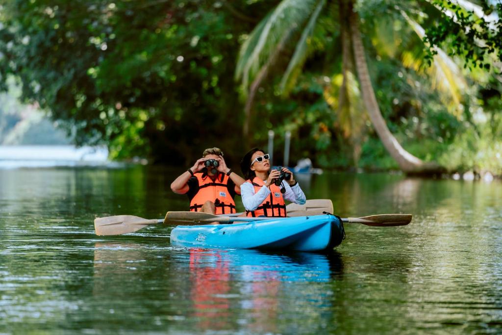 Divi cilvēki laivā pie Angsana Laguna Phuket, vērojot dabu.