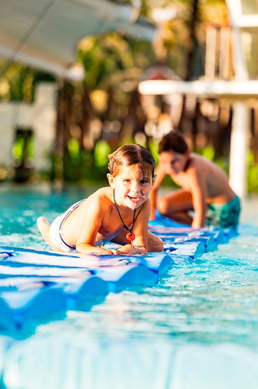 Bērni izklaidējas pie Angsana Laguna Phuket baseina, smejoties un spēlējot.