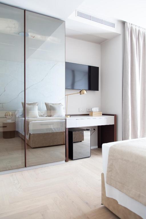 Mūsdienīga guļamistaba ar spoguļa skapjiem, gultu un televizoru, kas piekārts pie sienas. Interjerā izmantoti neitrāli toņi un eleganta apgaismojuma stāvbūve.