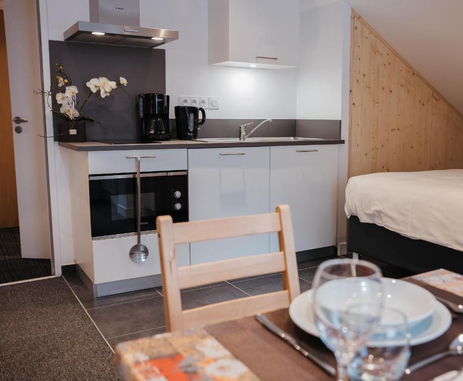 Mūsdienīgs virtuvītes stūris ar kafijas automātu, trauku mazgājamo mašīnu un elegantām dekorācijām, kas atrodas viesistabā kopā ar ēdamgaldu.