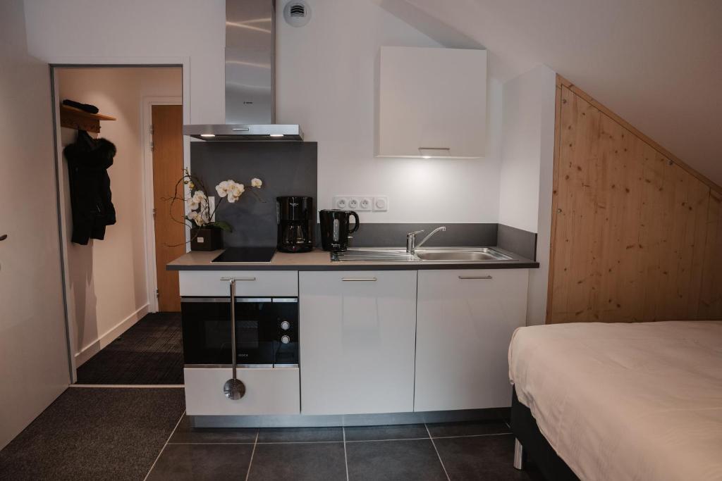 Mūsdienīgs virtuvītes stūris ar melnu darba virsmu, baltiem skapīšiem un modernu aprīkojumu, piemēram, kafijas automātu un mikroviļņu krāsni. Telpai ir arī koka elements un ērta gulta.