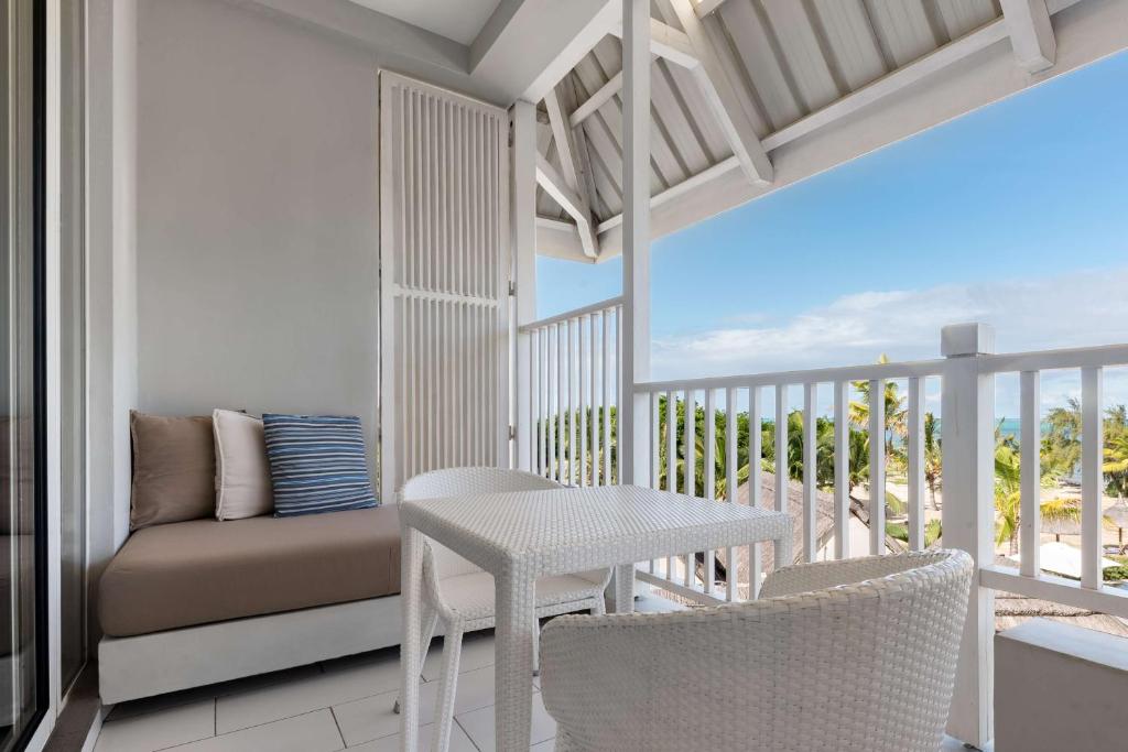 Balkons ar ērtu dīvānu un galdu, piedāvā skatu uz dabu un jūru, radot mierīgu atmosfēru atpūtai.
