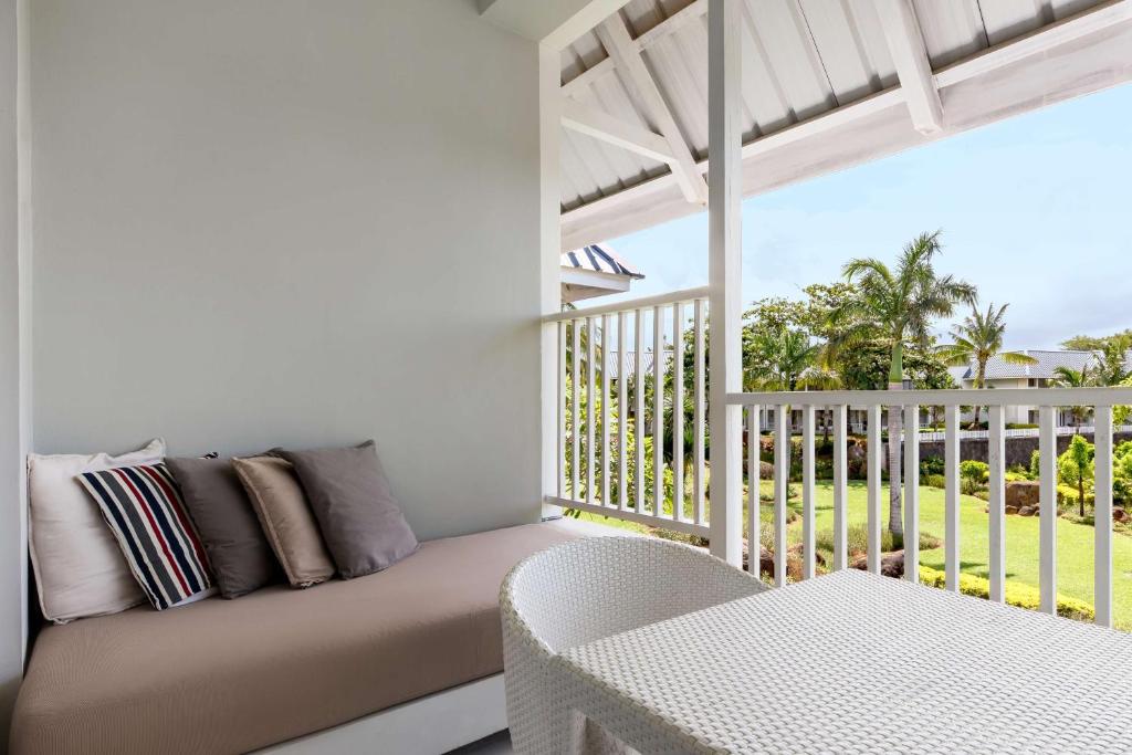 Balkons ar ērtu dīvānu un galdu, kas piedāvā skatu uz zaļo dārzu un palmām. Ideāla vieta relaksācijai un atpūtai.