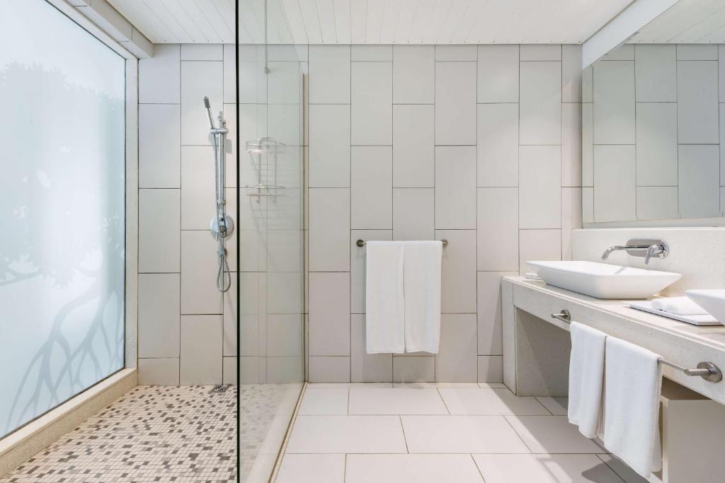 Eleganta un moderna vannas istaba ar stikla dušu, baltiem dvieļiem un minimālistisku dizainu. Gaišas flīzes un plaša spogulis piešķir telpai svaigumu un gaisīgumu.