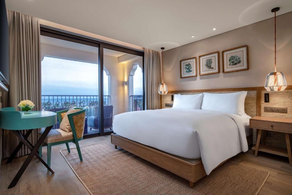 Mūsdienīgs viesnīcas numurs ar ietilpīgu gultu, elegantu galdu un krēslu, kā arī balkonu ar skatu uz jūru. Gaismas un dabīgie toņi rada mājīgu atmosfēru.