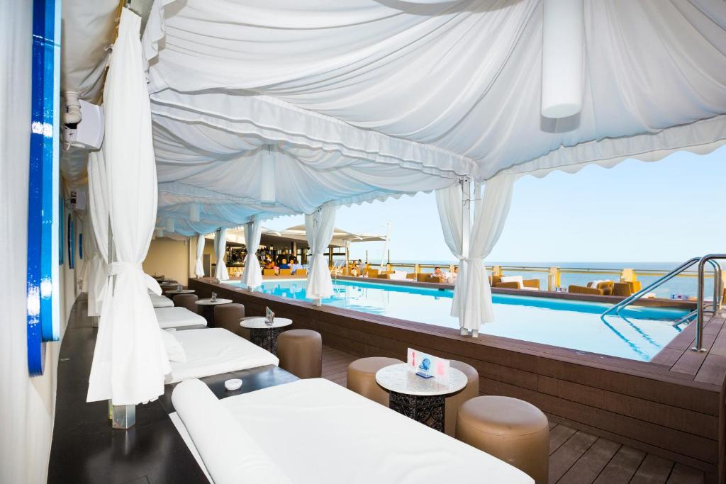 Baseina zona ar baltām teltīm un atpūtas krēsliem, skats uz ūdeni un relaksējošu atmosfēru. Ideāla vieta atpūtai un izklaidei.