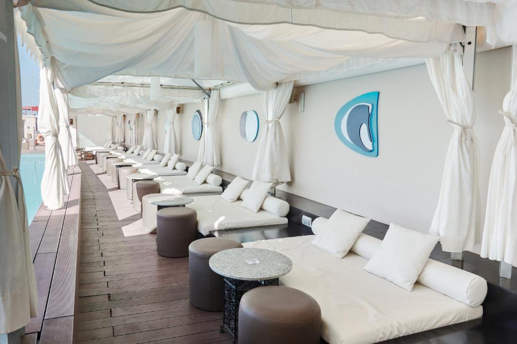 Atpūtas zona ar baltām nojumi un komfortablām guļammaisām, kas izklāta gar baseinu. Interjērā ir stilīgi galdi un spilveni, radot relaksējošu atmosfēru.