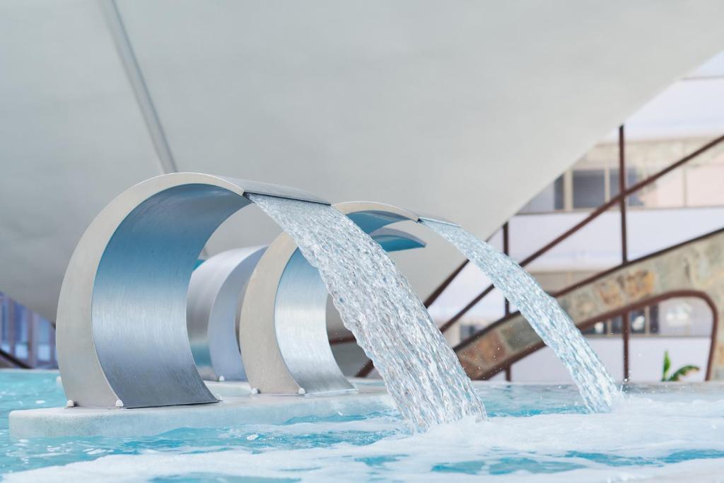 Mūsdienīga ūdens strūklaka ar metāla elementiem, kas plūst pāri, radot relaksējošu atmosfēru. Ideāli piemērota viesnīcu vai atpūtas vietu interjeram.