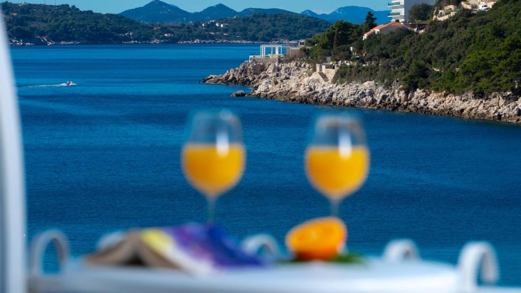 Divas dzirkstošas sulas glāzes ar skatu uz mierīgu jūru un kalnu ainavu. Ideāla vieta atpūtai un relaksācijai.