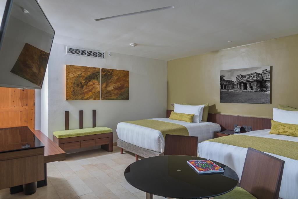 Mūsdienīgs viesnīcas numurs ar divām gultām, modernām mēbelēm un mākslas darbiem uz sienām. Telpa ir gaiša un komfortabla, ar ērtu sēžamo stūri un nelielu galdu.