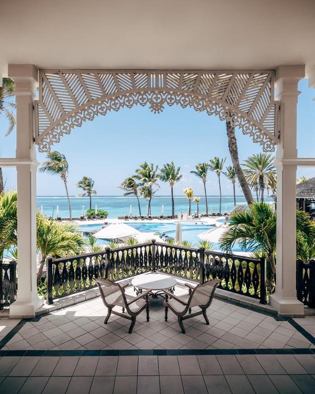 Skats uz pludmali un baseinu no grezna viesnīcas balkona, ar palmām un saules gultām kā fona. Ideāla vieta atpūtai un relaksācijai pie jūras.