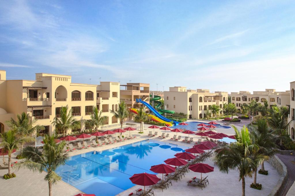 The Cove Rotana Resort baseins ar saulessargiem un palmām