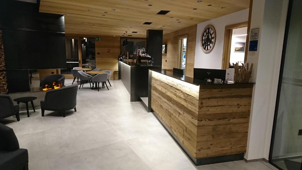 Mūsdienīgs viesnīcas vestibilis ar koka dekoriem, ērtām mēbelēm un bāra letēm, kas radīts relaksējošai atmosfērai. Gaisma un dizains veido patīkamu un aicinošu vidi.