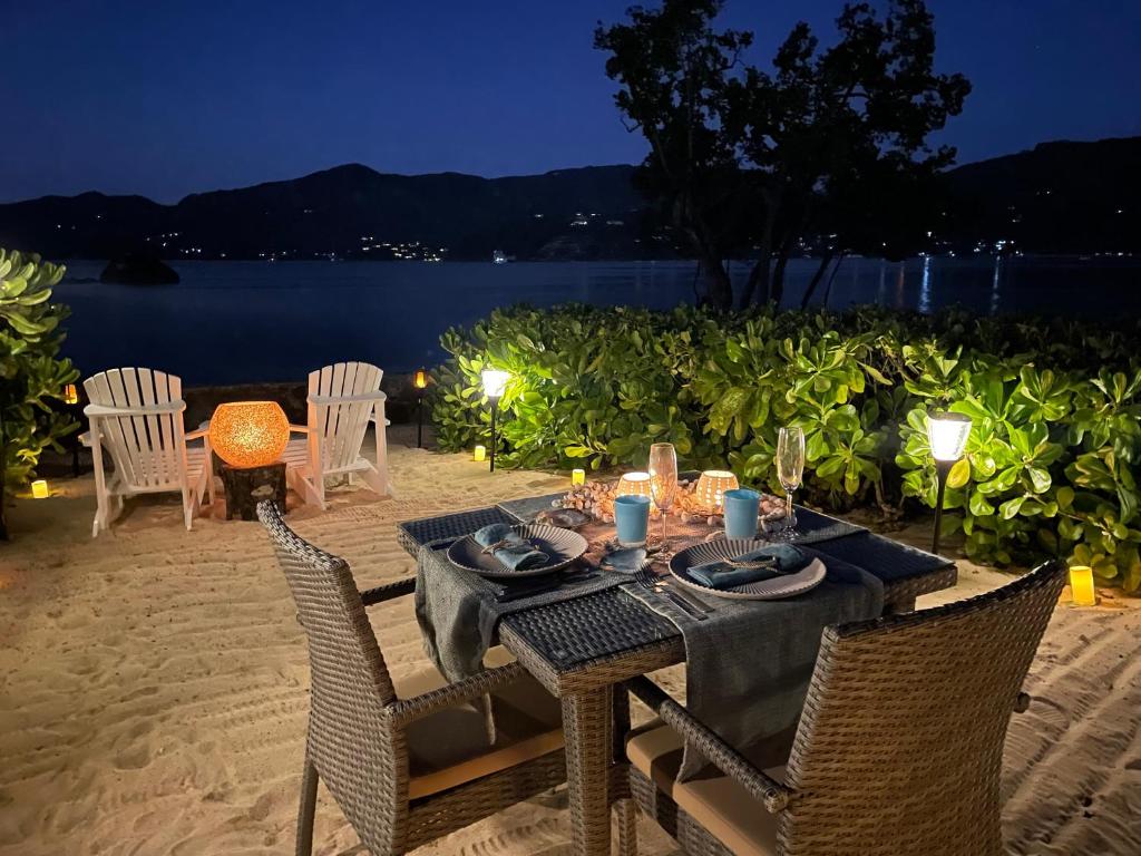 Romantiska vakariņas pludmalē ar skaistu skatu uz jūru, galda klājums ar sveču gaismu un zilo trauku. Ideāla atmosfēra mierīgai atpūtai.