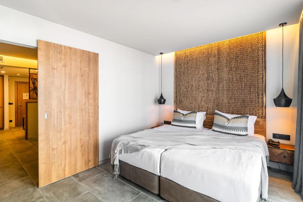 Mūsdienīgs guļamistabas interjers ar divguļamo gultu, dabīgiem materiāliem un siltu apgaismojumu. Telpa ir gaumīgi iekārtota ar koka durvīm un akcentiem.