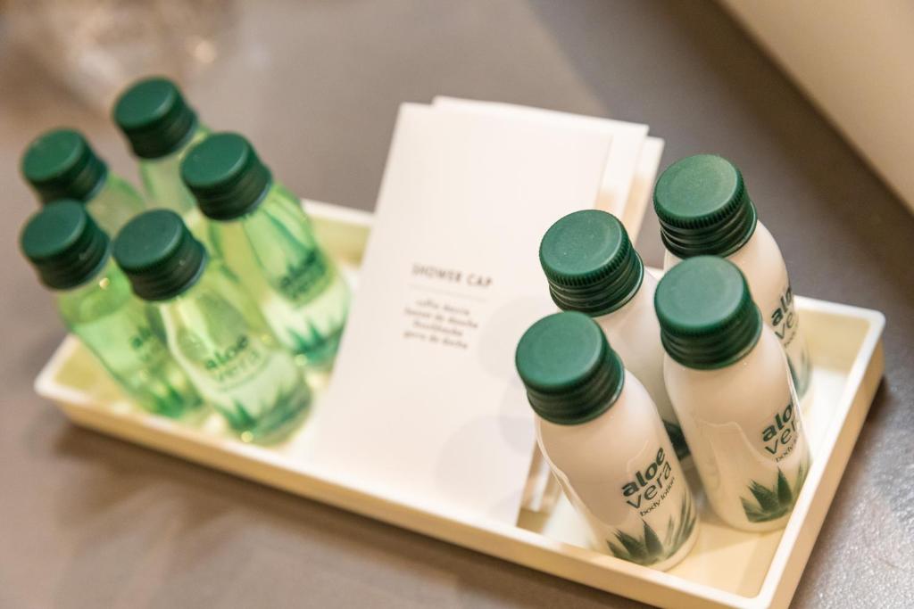 Tvertnē ir pieci zaļi aloe vera dzērieni un pieci baltas krāsas pudeļu dzērieni, kā arī uzraksts "DUŠAS CEPURE".