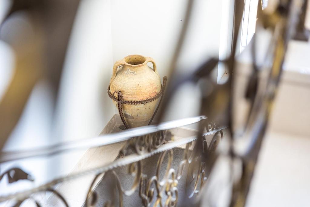 Keramikas trauks ar virvi stāv pie sienas, redzams caur dzelzs margām. Elegantā interjerā tas piešķir vintage šarmu.