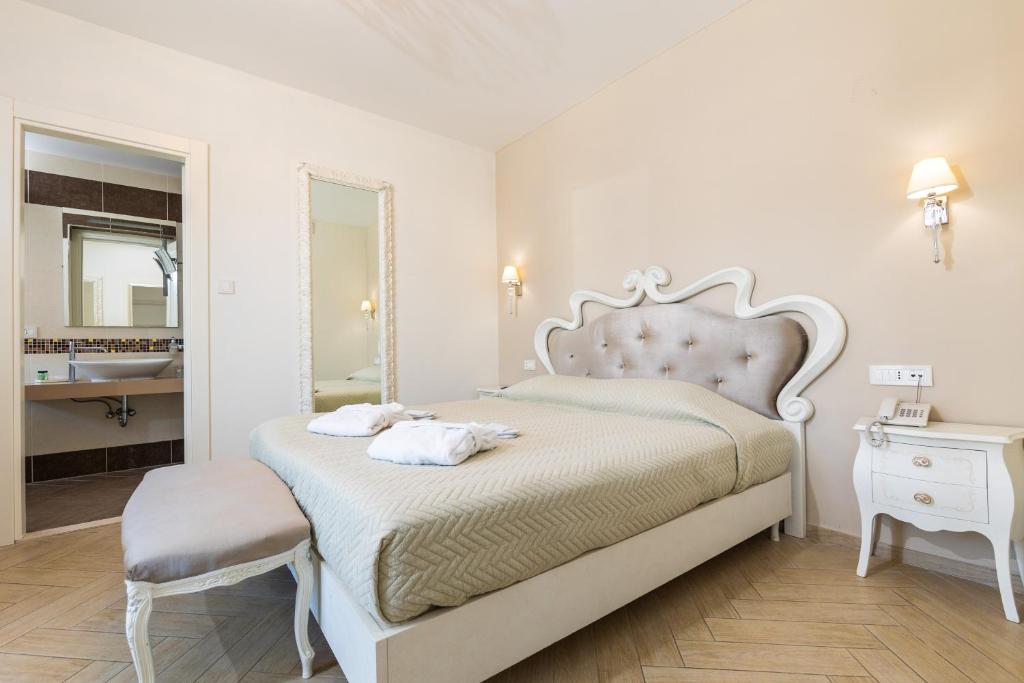 Mūsdienīgs guļamistabas interjers ar gultu, kas aprīkota ar elegantām detaļām, un pieejamu vannas istabu. Telpā ir arī spogulis un naktsgaldiņš.