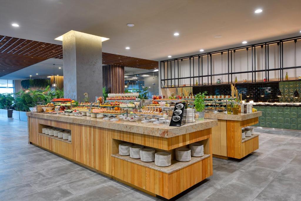 Mūsdienīgs bufetes galds ar plašu ēdienu klāstu, iekārtots elegantā restorānā. Izcelti dažādi salāti, deserti un dzērieni, radot viesmīlīgu atmosfēru.