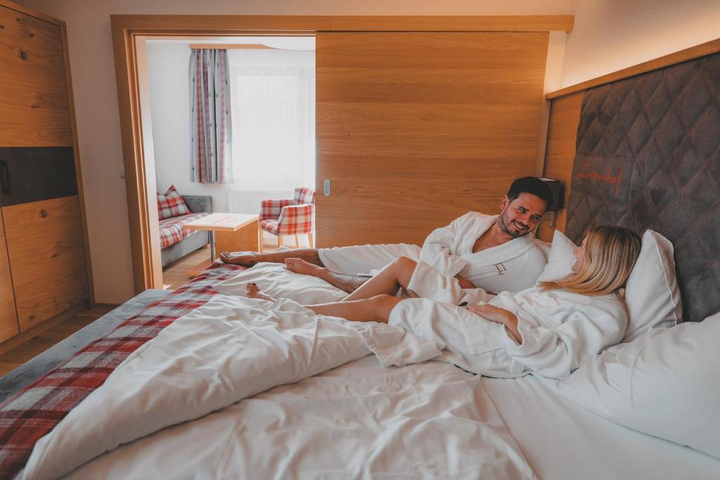 Mīļš pāris relaksējas gultā viesnīcas numurā, ģērbušies mīkstos halātos. Numurā ir gaišas krāsas interjers ar koka elementiem un brīnišķīgu skatu uz viesistabu.