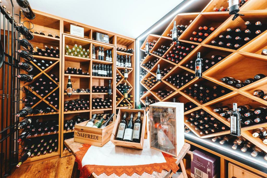Kvalitatīvs vīna pagrabs ar plašu vīnu izvēli, kas sakārtots koka plauktos. Izcelti dažādi vīni un dzērieni uz galda.