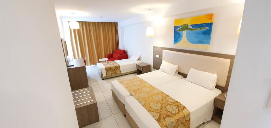 Mūsdienīga viesnīcas numura iekārtojums ar divām gultām, dīvānu un gaismas elementiem, kā arī mākslas darbu uz sienas, kas rada relaksējošu atmosfēru.