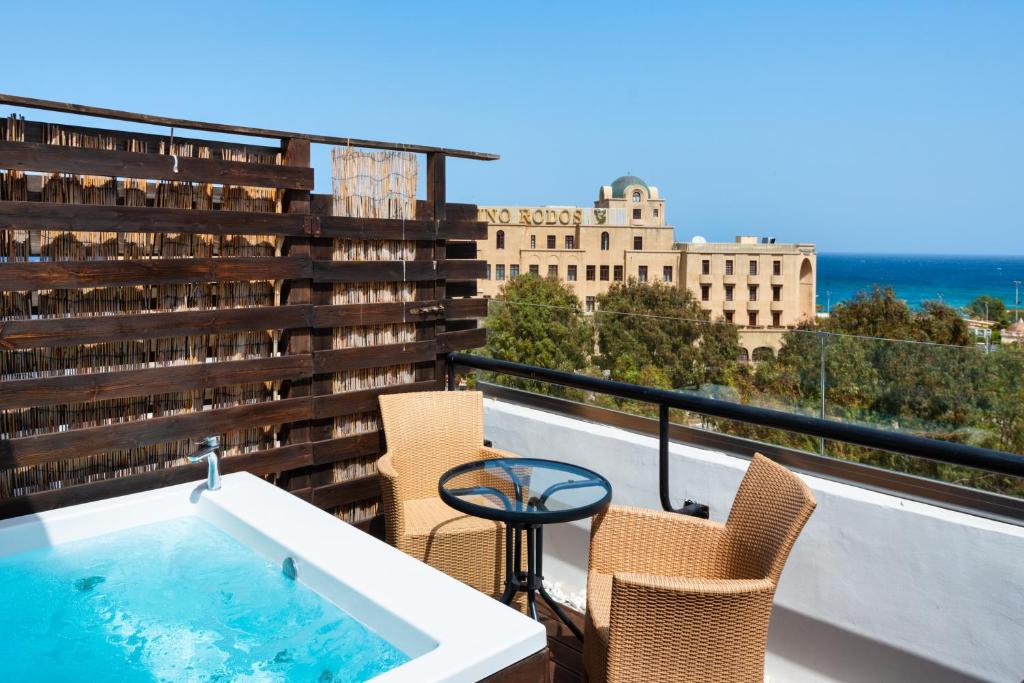 Terases skats ar burbuļvannu un ērtām mēbelēm, fonā redzama jūra un vēsturiska ēka. Ideāla vieta relaksācijai un atpūtai.