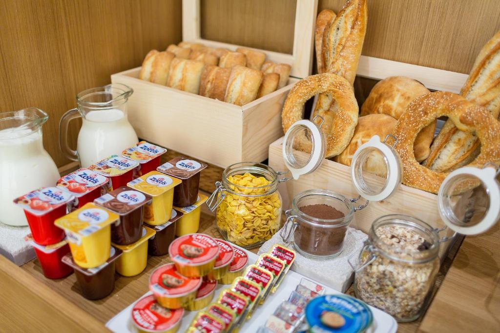 Brokastu galds ar dažādām delikatesēm, tostarp maizi, pienu, jogurtu, pārslām un konditorejas izstrādājumiem. Ideāla izvēle rīta maltītei.