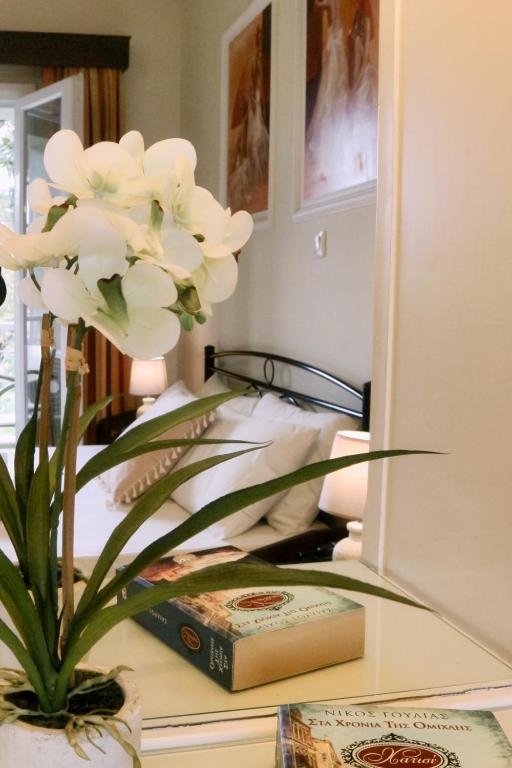 Gultas istaba ar orhideju, grāmatu un gaismas avotiem, kas rada mājīgu atmosfēru.