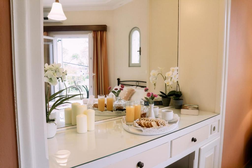 Elegantā guļamistaba ar gaisīgu atmosfēru, kurā redzams galda dekors ar ziediem, svečturiem un gardiem našķiem. Logu aizmugurē ir dabisks skats uz dārzu.