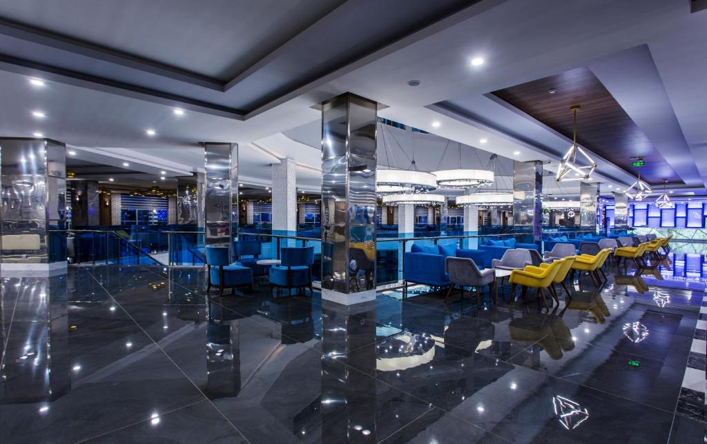 Mūsdienīgs restorāns ar elegantiem mēbeļu risinājumiem un spīdīgu grīdu, kurā apvienojas komforts un stilīgs dizains. Telpā ir daudz gaismas un krāsainas sēdvietas, radot patīkamu atmosfēru.