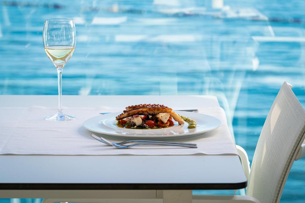 Gards jūras ēdiens ar baltu vīnu, pasniegts uz galda ar skatu uz ūdeni.