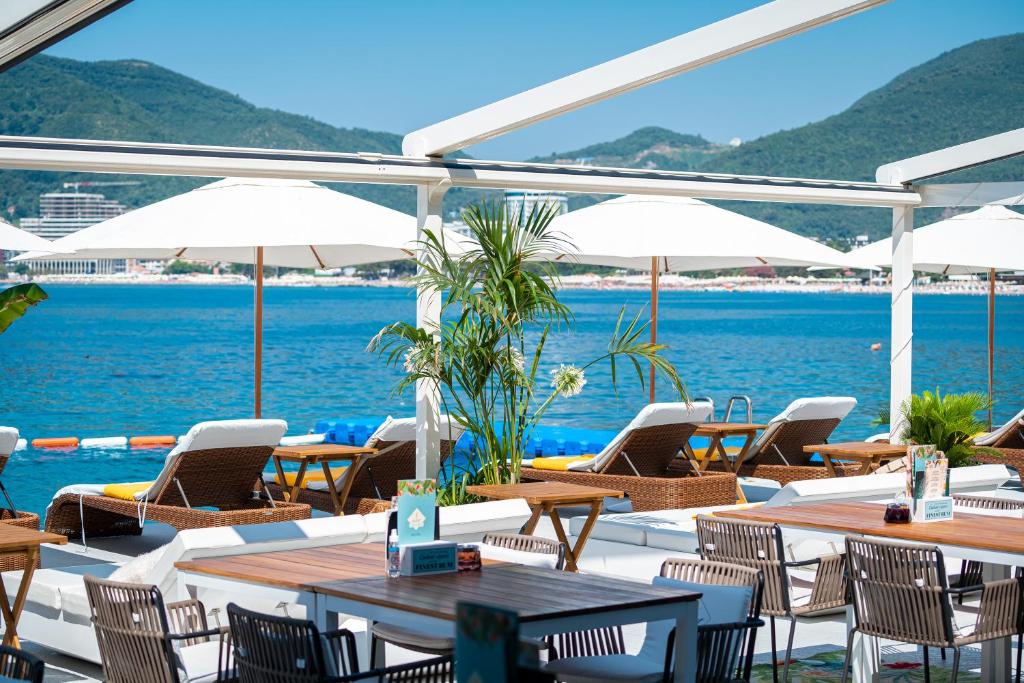 Atpūtas zona pie pludmales ar saulessargiem un guļamkrēsliem, skats uz jūru un kalniem fona. Ideāla vieta relaksācijai un atpūtai.