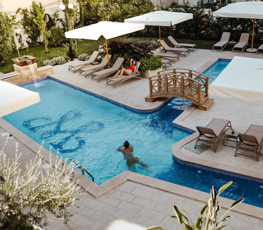 Baseins ar tiltiņu un saules gultām, kurā cilvēks peld, un otra persona atpūšas blakus. Ideāla atpūtas vieta dārzā.