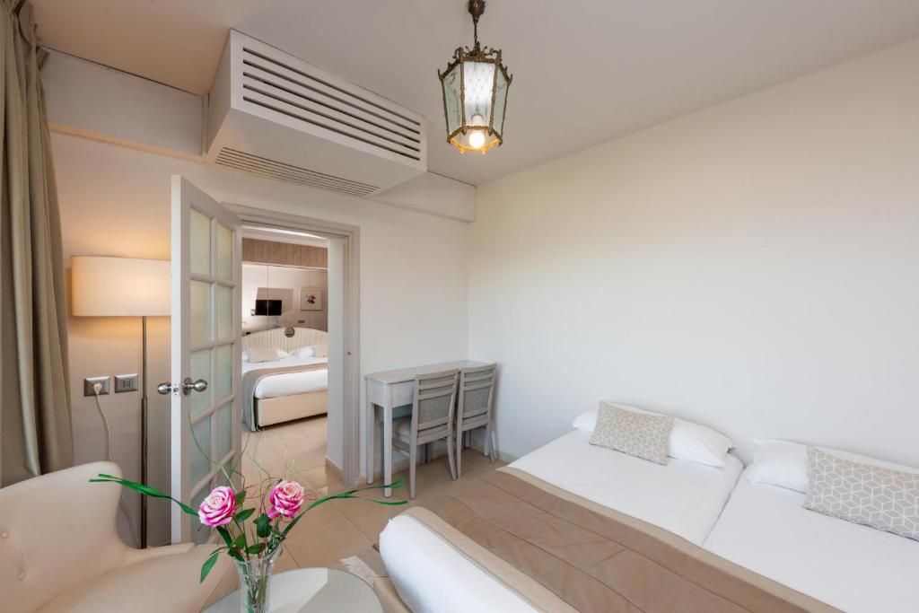 Mūsdienīgs viesnīcas numurs ar divām gultām, galdu un krēsliem, kā arī dekoratīvām rozēm uz galda. Gaismas avots no lampas un loga nodrošina gaišu un ērtu atmosfēru.