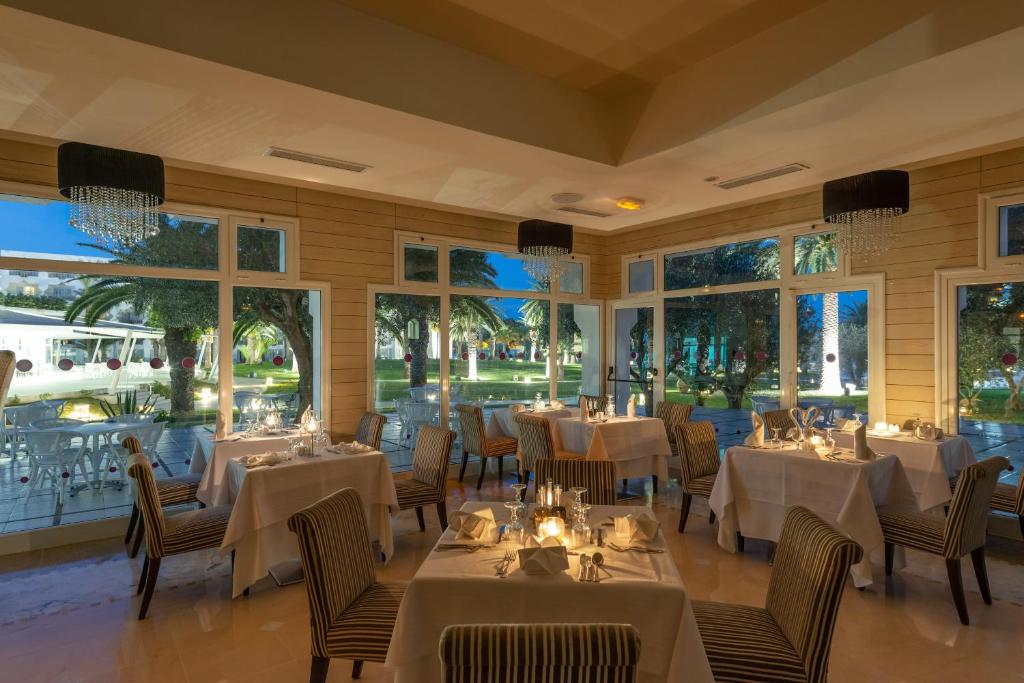 Eleganta restorāna iekārtojums ar logiem, kas paver skatu uz dārzu. Gaismas un sveces rada patīkamu atmosfēru romantiskai vakariņām.