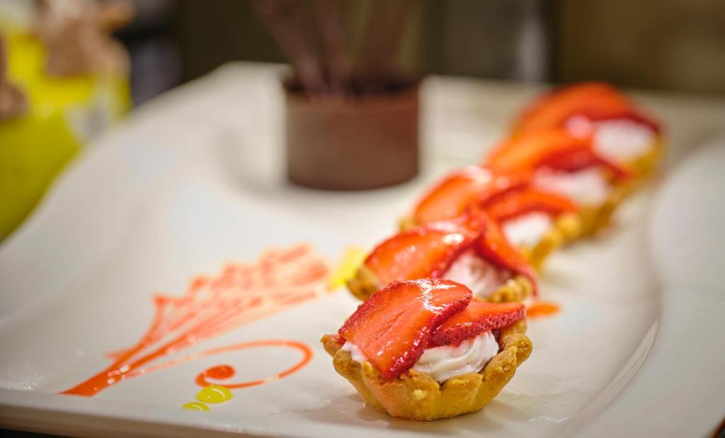 Kārtainā kūka ar krēmīgu pildījumu un svaigiem zemenēm, pasniegta uz dekorēta šķīvja.