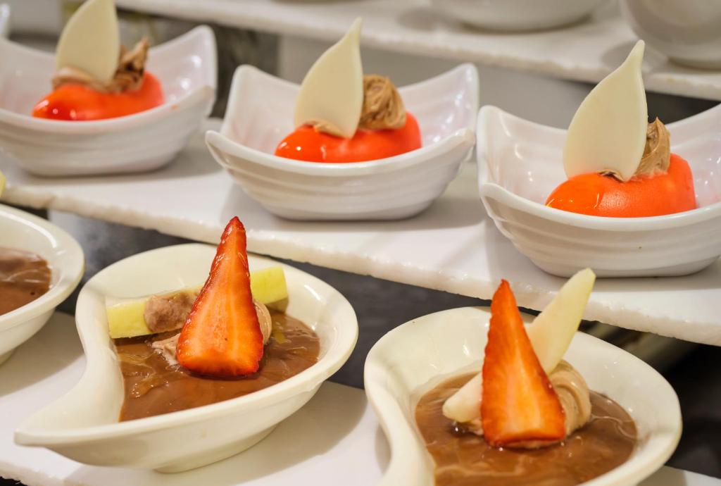 Saldējuma deserti ar augļu rotājumiem, kas pasniegti eleganti formas traukos. Krāsaini saldumi, ieskaitot šokolādes un augļu sastāvdaļas, radīt pievilcīgu izskatu.