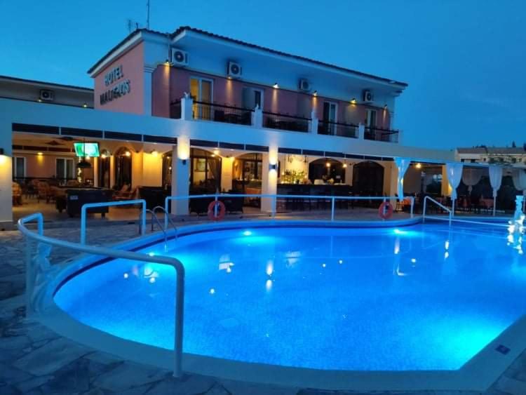 Viesnīcas "Maragkas" ārpuse ar skaistu baseinu, kas izgaismots zili, vakara apgaismojumā. Paviljons un terases rada patīkamu atmosfēru relaksācijai.