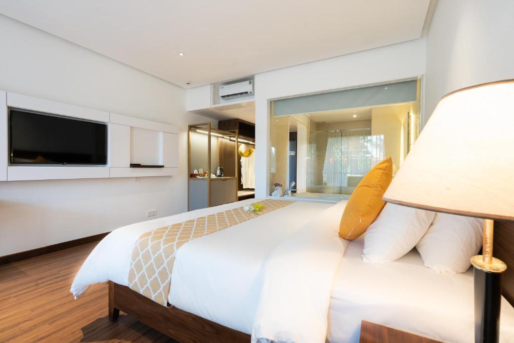 Mūsdienīgs viesnīcas numurs ar ērtu gultu, televizoru un skatu uz vannas istabu. Telpa ir gaiša un stilīga, radot patīkamu atmosfēru atpūtai.