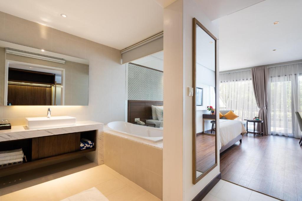 Mūsdienīgs viesnīcas numurs ar panorāmas skatu, iekļaujot elegantu vannas istabu ar vannu un izsmalcinātu interjeru. Gaismas pieplūdums un koka grīdas rada siltu un mājīgu atmosfēru.