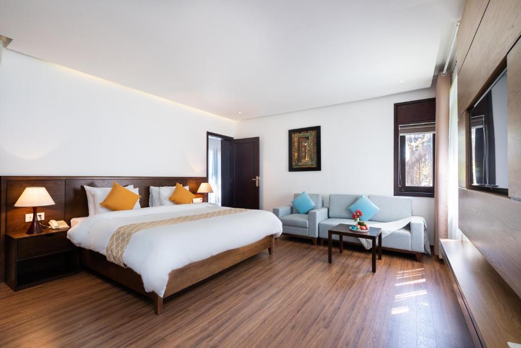 Moderns viesnīcas numurs ar divguļamo gultu, dīvānu un koka grīdu, kas nodrošina komfortu un eleganci. Telpā ir arī liela televizora siena un dabiska apgaismojuma avoti.