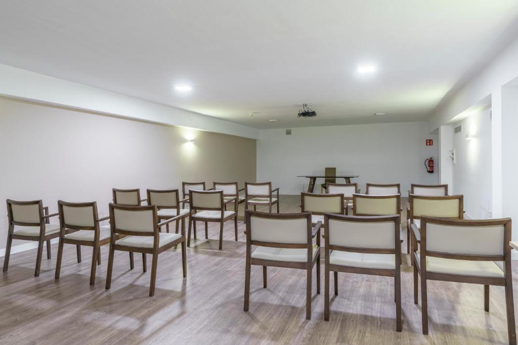 Konferences telpa ar vairākām koka krēslām un centrā esošu galdu. Gaisma ir spilgta, un telpa ir sakārtota, lai veicinātu sanāksmes vai prezentācijas.